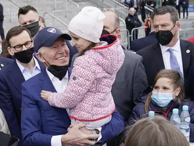 Presiden Amerika Serikat Joe Biden menggendong seorang gadis saat bertemu dengan pengungsi Ukraina pada kunjungan ke PGE Narodowy Stadium di Warsawa, Polandia, 26 Maret 2022. (AP Photo/Evan Vucci)