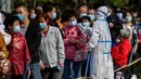Petugas medis mengukur suhu warga saat mereka antre untuk tes COVID-19 di dekat daerah perumahan di Qingdao, China, Senin (12/10/2020). Lebih dari 9 juta orang yang tinggal di kota Qingdao, menjalani tes virus Corona (COVID-19) secara massal setelah muncul kasus baru. (STR/AFP)
