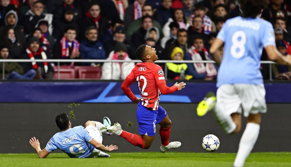 Pemain Atletico Madrid, Samuel Lino, terjatuh saat berebut bola dengan pemain Lazio, Pedro, pada laga grup E Liga Champions di Stadion Metropolitano, Madrid, Kamis (14/12/2023). Atletico menang dua gol tanpa balas. (AP Photo/Pablo Garcia)