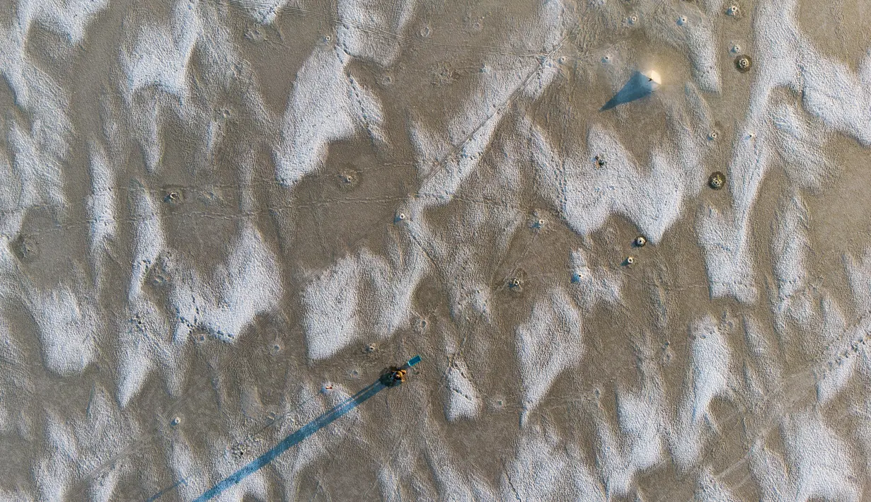 Seorang pria sedang memancing di tengah Laut Bothnia yang membeku di dekat Vaasa, Finlandia, 28 Desember 2018. Sebelum memancing, mereka membuat lubang menggunakan bor untuk memberikan umpannya kepada ikan buruan. (OLIVIER MORIN / AFP)