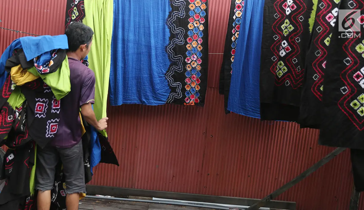 Pekerja mengangkat kain sasirangan yang telah dijemuri di kawasan Banjarmasin, Kalimantan Selatan, Senin (26/3). Kain sasirangan ini diwariskan secara turun temurun sejak abad XI. (Liputan6.com/Immanuel Antonius)