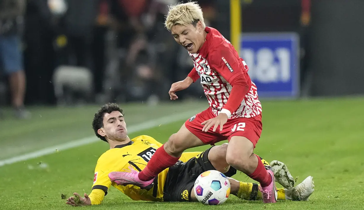 Pemain Borussia Dortmund, Mateu Morey, berebut bola dengan pemain SC Freiburg, Ritsu Doan, pada laga Liga Jerman di Stadion Signal Iduna Park, Sabtu (10/2/2024). (AP Photo/Martin Meissner)