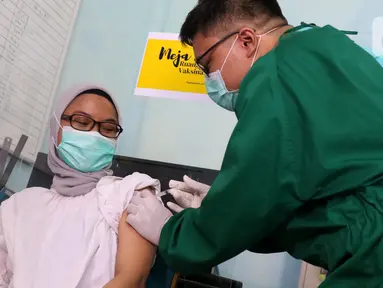 Vaksinator menyuntikkan vaksin COVID-19 kepada tenaga kesehatan yang bertugas di Puskesmas Jurang Mangu, Tangerang Selatan, Jumat (15/1/2021). Program vaksinasi COVID-19 tahap pertama kepada tenaga kesehatan mulai dilakukan di berbagai daerah di Indonesia. (Liputan6.com/Angga Yuniar)