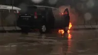 Mobil terbakar dengan kondisi pintu depan bagian sopir terbuka.