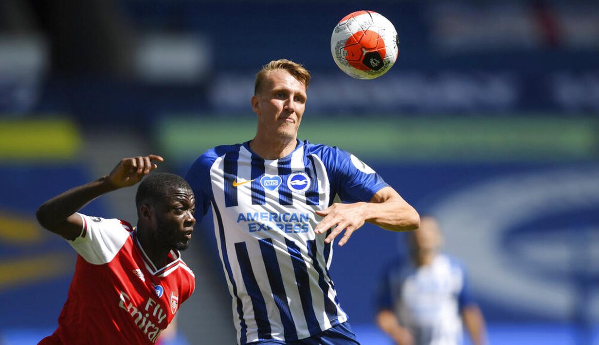 Pemain Brighton & Hove Albion, Dan Burn, berebut bola dengan pemain Arsenal, Nicolas Pepe, pada laga Premier League di Stadion Falmer, Sabtu (20/6/2020). Arsenal kalah 1-2. (AP/Mike Hewitt)
