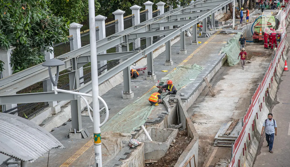 Sejumlah pekerja menyelesaikan pembangunan selter di kawasan Stasiun Palmerah, Jakarta, Selasa (2/2/2021). Penataan kawasan Stasiun Palmerah mencakup pembangunan selter untuk bus, angkot, dan ojek online. (Liputan6.com/Faizal Fanani)