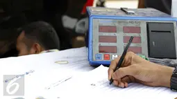 Petugas saat mengisi hasil uji emisi yang dilakukan di Depok, Rabu (4/11/2015).Kemeterian Lingkungan Hidup dan Kehutanan RI gelar uji emisi kendaraan roda empat secara gratis di Jalan Juanda, Depok. (Liputan6.com/Yoppy Renato)