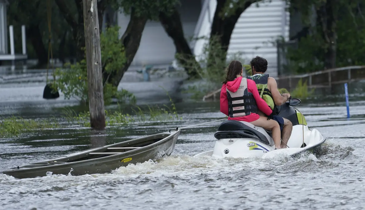 Penduduk lokal dengan jet ski menarik kano ke rumah yang terendam banjir saat gelombang luar Badai Ida tiba Bay Saint Louis, Miss (29/8/2021). (AP Photo/Steve Helber)