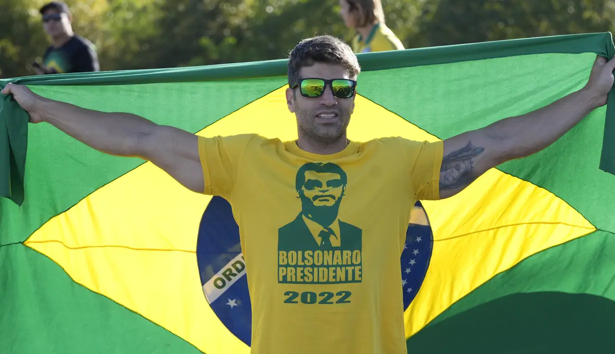 Ratusan pendukung yang mengenakan warna nasional Brasil, kuning dan hijau, meneriakkan yel-yel untuk Bolsonaro ketika mereka menunggu kedatangannya, tetapi kembalinya Bolsonaro tidak menarik kerumunan massa yang diharapkan oleh banyak sekutunya. (AP Photo/Eraldo Peres)