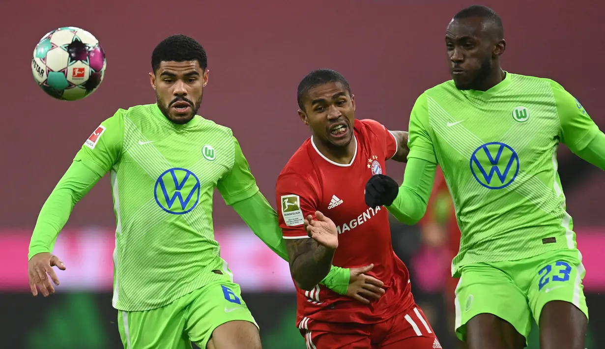 Gelandang Bayern Munchen, Douglas Costa (tengah) dijepit dua pemain Vfl Wolfsburg, Paulo Otavio (kiri) dan Josuha Guilavogui pada laga Liga Jerman 2020/2021 di Munich, Jerman (16/12/2020). Douglas Costa didatangkan Munchen dari Shakhtar Donetsk pada awal musim 2015/2016 dengan mahar 30 juta euro atau kini setara Rp501 miliar. Hanya tampil dua musim pada 2015/2016 dan 2016/2017 plus setengah musim berstatus pinjaman dari Juventus pada 2020/2021, ia total tampil dalam 97 laga dengan torehan 15 gol dan 30 assist. (AFP/Pool/Christof Stache)