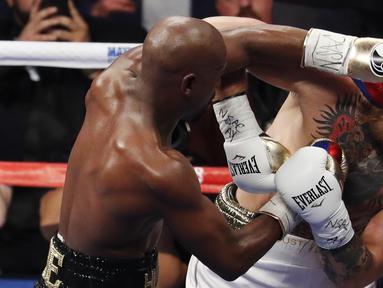 Floyd Mayweather Jr. melepaskan pukulan ke wajah Conor McGregor pada gelaran Tinju Dunia super welterweight boxing di MGM Arena, Las Vegas, (26/8/2017). Mayweather menang TKO atas McGregor. (AP/Eric Jamison)