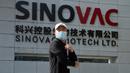Seorang pekerja melewati logo di luar pabrik vaksin SinoVac di Beijing, Kamis (24/9/2020). Perusahaan farmasi China, Sinovac mengatakan vaksin virus corona yang dikembangkannya akan siap didistribusikan ke seluruh dunia, termasuk AS, pada awal 2021. (AP Photo/Ng Han Guan)
