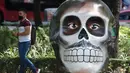 Seorang pria melewati tengkorak yang dihias selama pameran edisi keempat "Mexicraneos" (Mexisculls) di Reforma Avenue, Mexico City pada 23 Oktober 2020. Pameran tersebut karya seniman dari berbagai bagian negara Meksiko, dan juga dari Amerika Serikat serta Venezuela. (ALFREDO ESTRELLA/AFP)