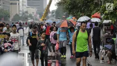 Warga melakukan olahraga dalam kegiatan rutin hari bebas kendaraan bermotor atau car free day di kawasan Bunderan HI, Jakarta, Minggu (4/2). Walaupun gerimis mengguyur tidak menyurutkan minat masyarakat yang melakukan olahraga.(Liputan6.com/Faizal Fanani)