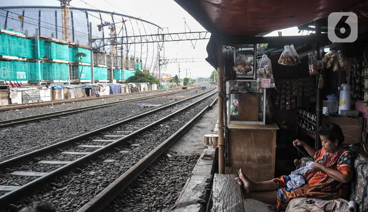 Aktivitas warga penghuni bantaran rel yang berada dekat dengan proyek pembangunan Kampung Susun Bayam, Papanggo, Tanjung Priok, Jakarta Utara, Selasa (12/7/2022). Kampung Susun Bayam rencananya memiliki empat lantai yang diperuntukkan bagi 138 keluarga dan ditargetkan rampung pada September 2022. (merdeka.com/Iqbal S. Nugroho)