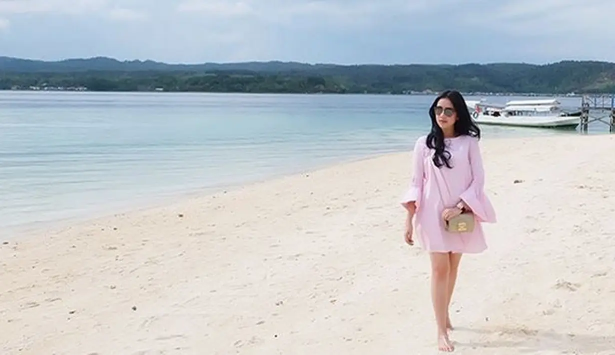 Masih berada di tepi pantai, Tistha tampil dengan mini dress berwarna pink yang berlengan panjang. Tanpa memakai alas kaki, Tistha yang berada di panas terik memakai sun glasses saat berjalan di pasir pantai. (Instagram/tisthanurma)