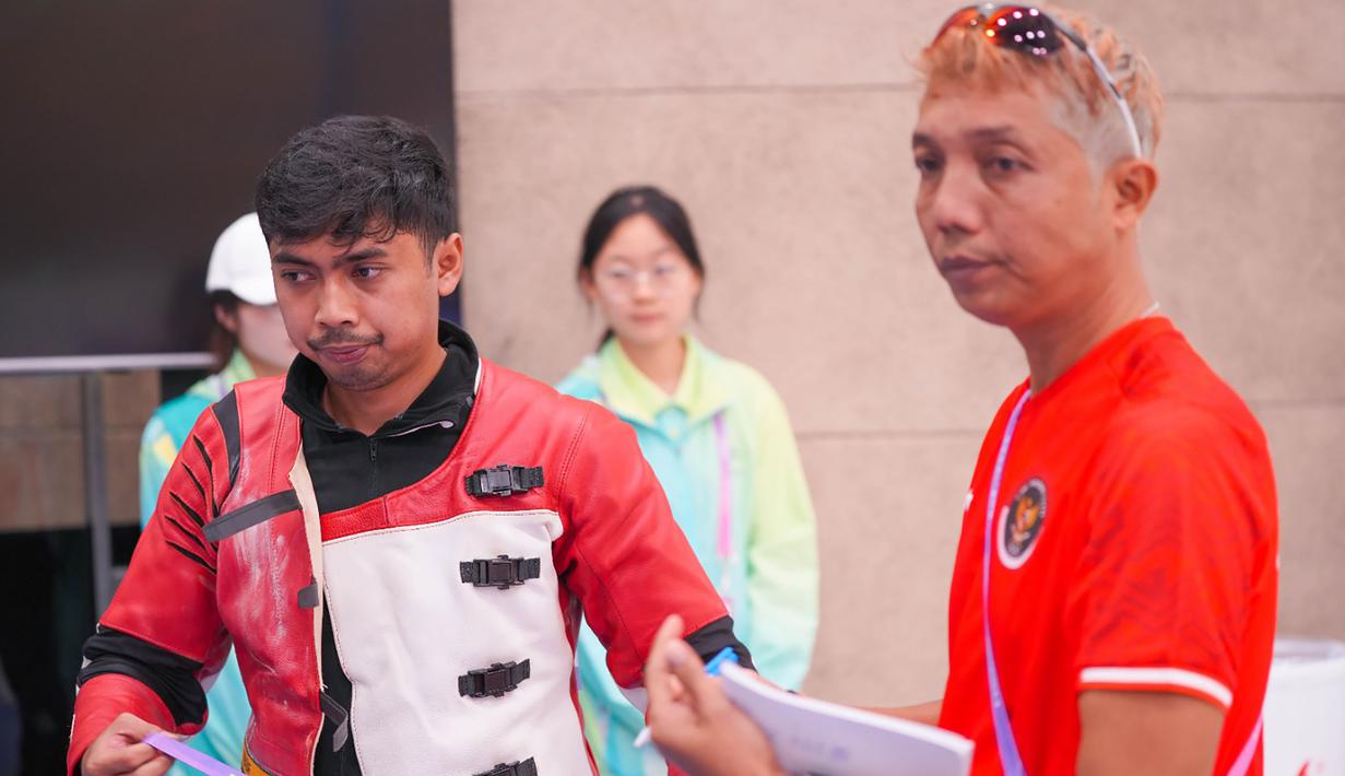 Petembak Indonesia, Muhammad Sejahtera Dwi Putra didampingi ofisial tim saat berlomba di nomor perorangan 10 meter running target putra cabang menembak Asian Games Hangzhou 2022 di Fuyang Yinhu Sports Centre, Hangzhou, China, Senin (25/9/2023). (NOC Indonesia)