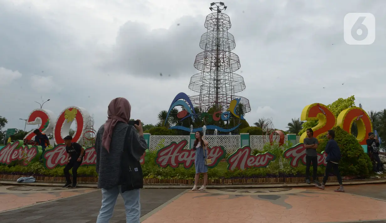 Pengunjung berfoto jelang malam pergantian tahun di Kawasan Pantai Lagoon, Taman Impian Jaya Ancol, Jakarta, Selasa (31/12/2019). Ribuan pengunjung menikmati malam pergantian tahun 2019 menuju 2020 dengan menyalakan kembang api. (merdeka.com/Imam Buhori)