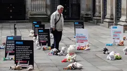 Seorang pria melewati boneka mainan yang diletakkan di halaman gedung Kongres Kolombia saat aksi protes di Bogota, Selasa (20/11). Protes ini bertujuan untuk mendorong pengaduan kasus pelecehan anak di hadapan pihak berwenang Kolombia (DANIEL MUNOZ/AFP)