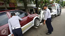 Petugas menderek kendaraan roda empat yang parkir sembarangan di kawasan Jatinegara, Jakarta Timur, Senin (28/12). Meski sudah ditertibkan, pengendara masih tak menghiraukan peraturan tersebut yang mengakibatkan kemacetan. (Liputan6.com/Immanuel Antonius)