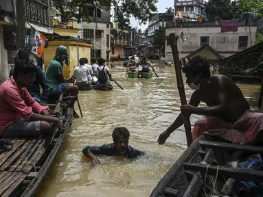 Warga menaiki perahu di atas jalan yang terendam banjir menyusul hujan lebat di Ghatal, distrik Paschim Medinipur, sekitar 100 km dari Kolkata (2/8/2021). Banjir parah akibat hujan lebat membuat jalanan di Ghatal berubah bak sungai. (AFP/Dibyangshu Sarkar)