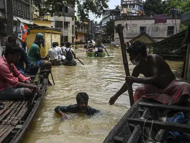 Warga menaiki perahu di atas jalan yang terendam banjir menyusul hujan lebat di Ghatal, distrik Paschim Medinipur, sekitar 100 km dari Kolkata (2/8/2021). Banjir parah akibat hujan lebat membuat jalanan di Ghatal berubah bak sungai. (AFP/Dibyangshu Sarkar)
