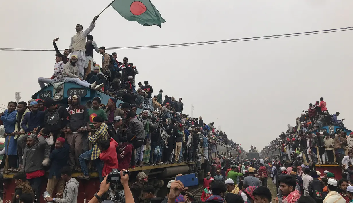 Seorang pria mengibarkan bendera Bangladesh ketika menaiki kereta yang penuh sesak untuk kembali ke rumah setelah menghadiri pertemuan Muslim tahunan 'Biswa Ijtema' di Dhaka, Minggu (12/1/2020). Biswa Ijtema dianggap sebagai salah satu pertemuan terbesar umat Muslim. (AP/Al-emrun Garjon)