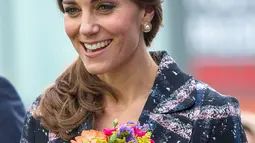 Kate Middleton terlihat cantik membawa bunga saat mengunjungi Meseum Nasional Sepak Bola di Manchester, Inggris (14/10). (Reuters/Charlotte Graham)