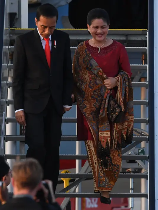 Presiden RI, Joko Widodo didamping Ibu Negara Iriana Widodo menuruni tangga pesawat saat tiba di bandara Hamburg, Jerman utara (6/7). Sejumlah pemimpin negara berkumpul dalam KTT G20 pada 7-8 Juli 2017. (AFP Photo/Patrik Stollarz)