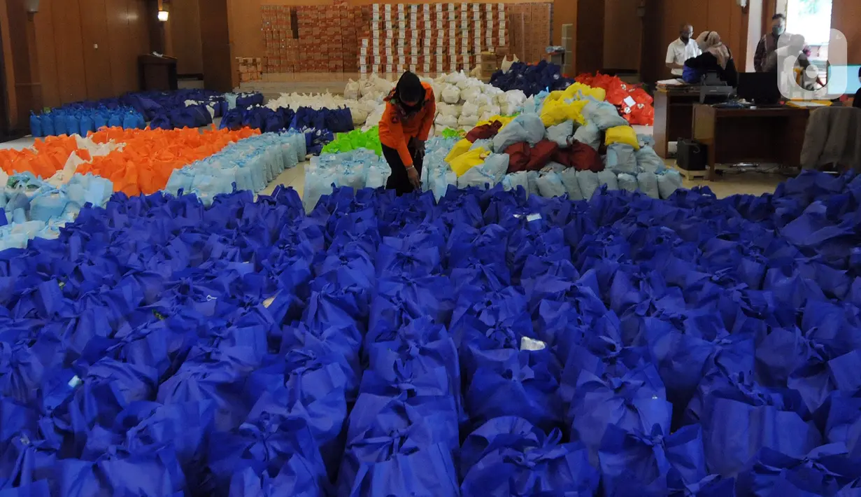 Petugas menata bansos berupa bahan pangan untuk didistribusikan kepada warga terpapar COVID-19 yang menjalani isolasi mandiri di rumah di Gedung Wanita, Kota Bogor, Jumat (9/7/2021). Setiap harinya, bonsos dibagikan kepada warga melalui keluarahan. (merdeka.com/Arie Basuki)