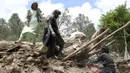 Penduduk desa mengumpulkan barang-barang dari bawah puing-puing sebuah rumah yang hancur akibat gempa bumi di Distrik Spera, bagian barat daya Provinsi Khost, Afghanistan, 22 Juni 2022. Gempa menewaskan lebih dari 1.000 orang dan melukai 1.500 lainnya. (AP Photo)