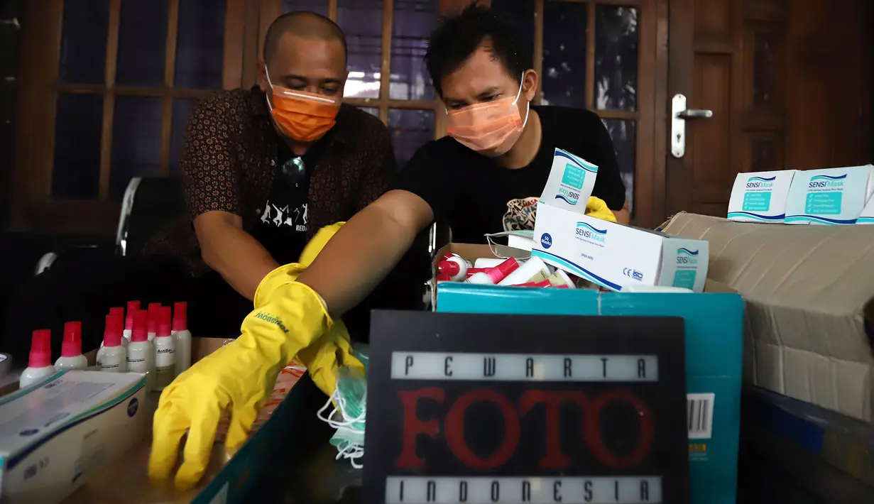 Ketua Pewarta Foto Indonesia (PFI) Reno Esnir (kiri) merapikan masker dan hand sanitizer untuk dibagikan kepada jurnalis foto di Jakarta, Jumat (20/3/2020). PFI berupaya untuk bisa mengirimkan masker dan hand sanitizer ke daerah lain selain Jakarta.  (Foto: Dok. Pewarta Foto Indonesia)