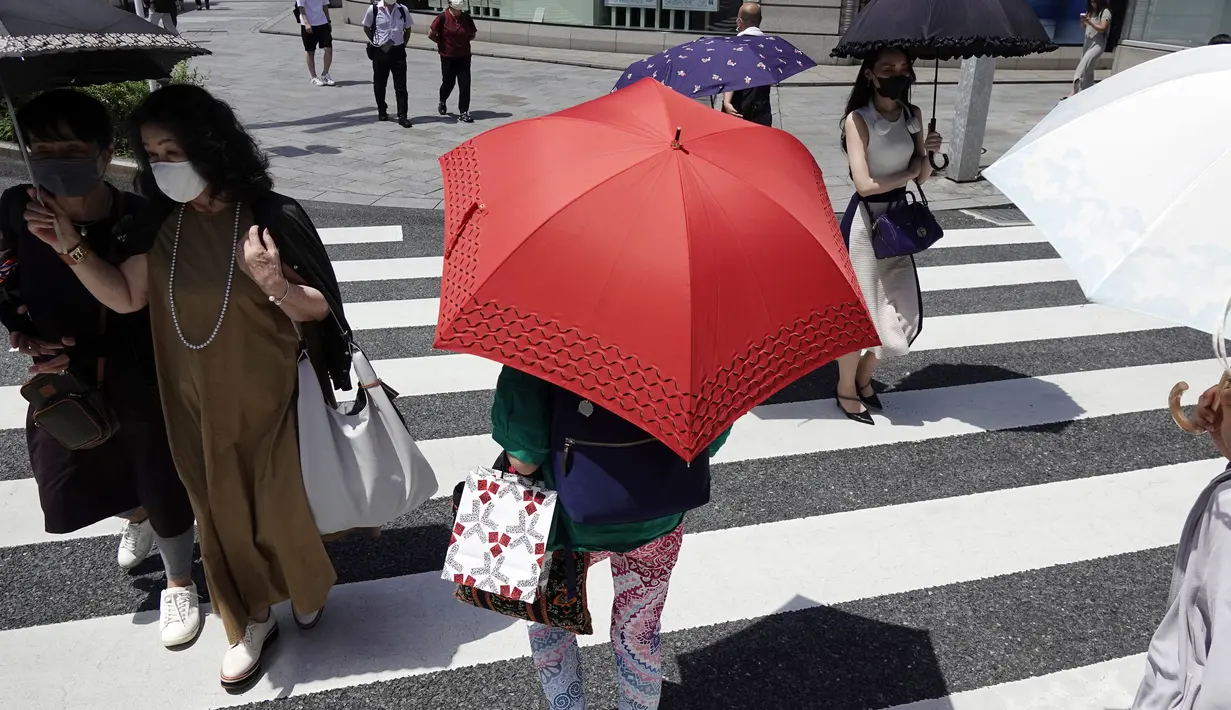 Orang-orang berjalan di atas penyeberangan pejalan kaki di bawah terik matahari di Tokyo, Selasa (10/8/2021). Menurut biro meteorologi Jepang, cuaca panas panas terus berlanjut di wilayah metropolitan saat suhu naik menjadi 38 derajat Celcius (100,4 derajat Fahrenheit). (AP Photo/Eugene Hoshiko)
