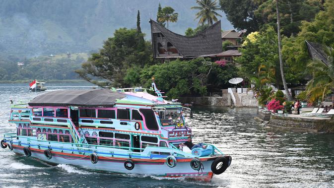 Gambar pada 3 April 2019 menunjukkan sebuah kapal wisata tiba di Pulau Samosir, pulau vulkanik di tengah Danau Toba, provinsi Sumatera Utara,  3 April 2019. Di kalangan masyarakat Batak sendiri, Danau Toba ibaratnya inang atau ibu yang akan selalu menanti dengan keindahannya. (GOH CHAI HIN / AFP)