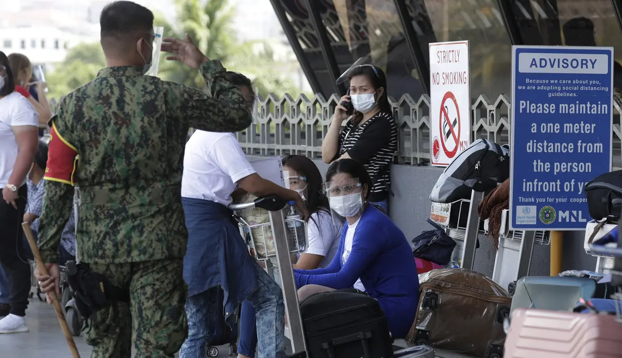 Petugas mengingatkan orang untuk mempraktikkan protokol kesehatan di Bandara Internasional Manila, Rabu (17/3/2021). Warga asing dan warga Filipina yang kembali luar negeri tidak akan dapat memasuki negara itu dari 20 Maret hingga 19 April, kata gugus tugas virus corona. (AP Photo/Aaron Favila)