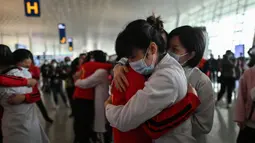 Staf medis dari Provinsi Jilin (merah) memeluk perawat dari Wuhan setelah bekerja bersama menangani pandemi Covid-19 saat upacara pelepasan di Bandara Tianhe, Wuhan, provinsi Hubei, Rabu (8/4/2020). Pemulangan staf medis ini bersamaan dengan dicabutnya status lockdown Wuhan. (Hector RETAMAL/AFP)