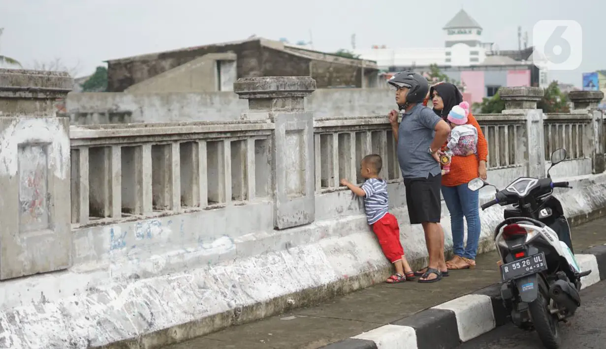 Pengendara sepeda motor mengamati banjir yang menggenangi kawasan Rawajati dari atas flyover di Jakarta Timur, Rabu (1/1/2020). Banjir yang berasal dari luapan Sungai Ciliwung itu menjadi daya tarik tersendiri bagi sebagian pemotor yang melintasi di flyover tersebut. (Liputan6.com/Immanuel Antonius)
