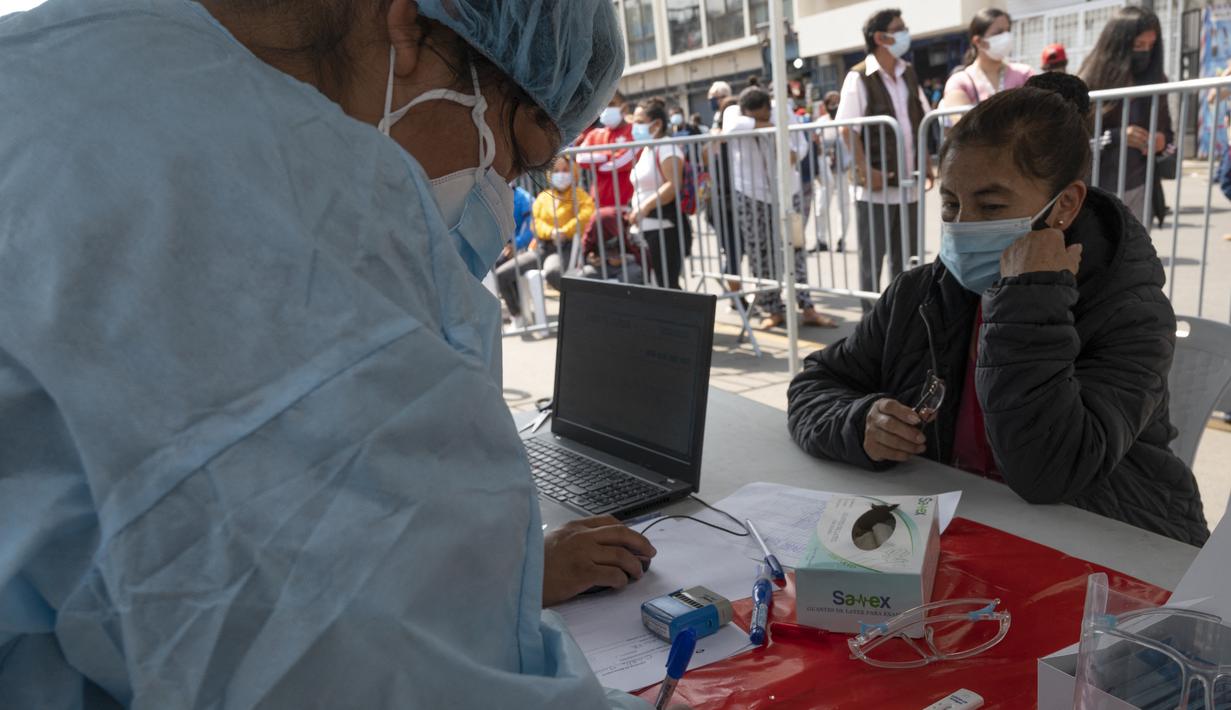 Seorang wanita menunggu untuk swab COVID-19 di sebuah pusat kesehatan darurat di sebuah jalan di pusat kota Lima, Rabu (5/1/2022). Peru melaporkan negara itu secara resmi menghadapi gelombang ketiga COVID-19 karena peningkatan kasus infeksi setelah perayaan Natal dan Tahun Baru. (Cris BOURONCLE/AFP)