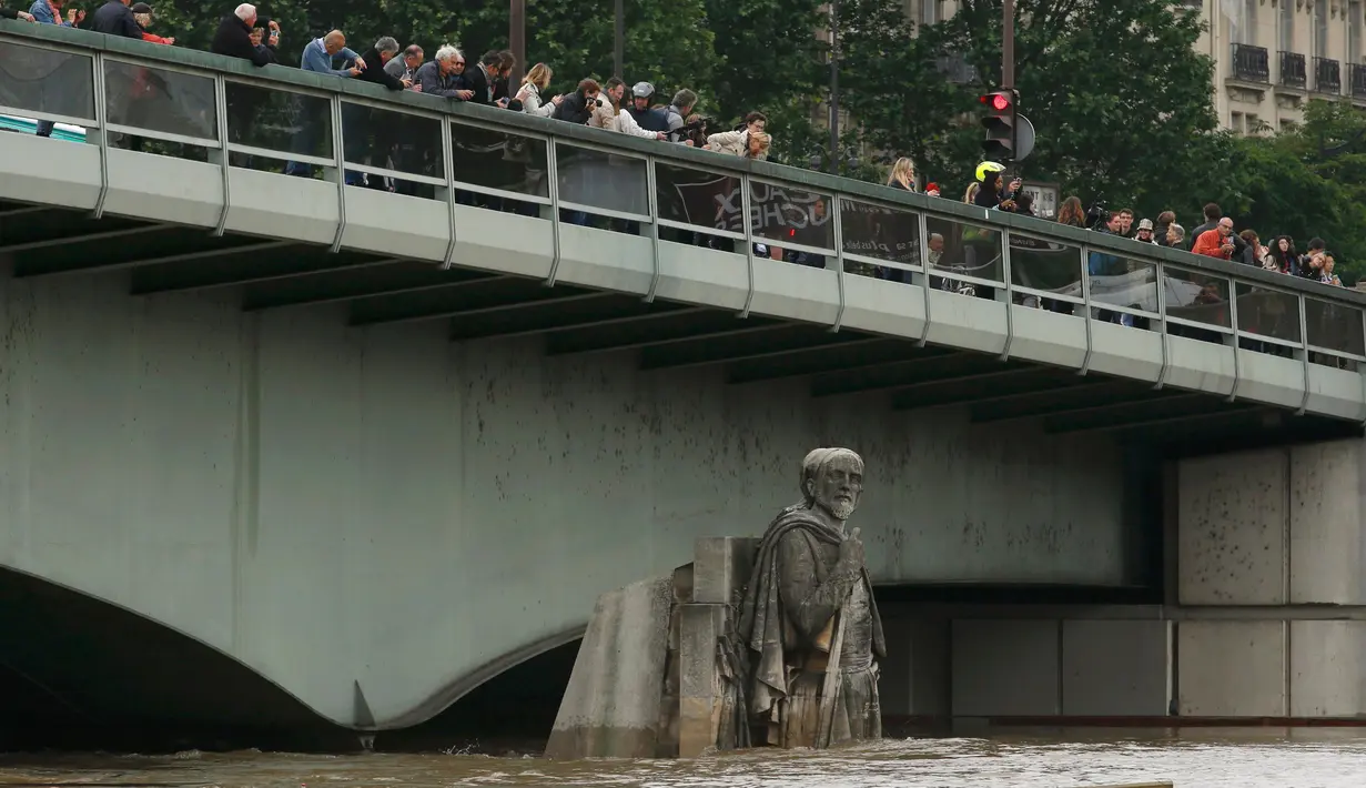 Warga melihat patung Zouave yang terendam banjir dari Sungai Seine setelah hampir setiap hari hujan lebat di Paris, Prancis, (3/6). Banjir yang merendam sebagian wilayah Prancis Sejauh ini sudah dua orang tewas. (REUTERS/Pascal Rossignol)