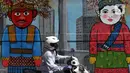 Pengendara sepeda motor melintas di depan mural Kota Jakarta, Tanah Kusir, Kebayoran Lama, Jakarta, Jumat (26/11/2021). Mural tersebut bertemakan Kota Jakarta dengan gambar ikon seperti ondel-ondel, Monas hingga transportasi. (Liputan6.com/Herman Zakharia)