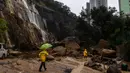 Hujan lebat mulai mengguyur Hong Kong pada Kamis (7/9) menjelang tengah malam. Para pekerja berjalan melewati tanah longsor setelah hujan badai di Hong Kong, Jumat, 8 September 2023. (AP Photo/Louise Delmotte)