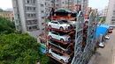 Struktur dari parkir bertingkat tiga dimensi yang terletak di antara bangunan tempat tinggal apartemen di Shenyang, Provinsi Liaoning, China (19/6). Fasilitas parkir yang tak memakan banyak tempat ini disediakan untuk umum. (AFP Photo/Str/China Out)