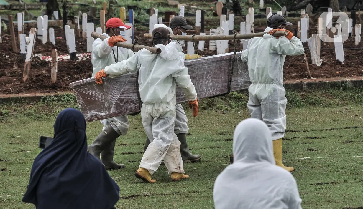 Petugas mengenakan APD lengkap membawa peti jenazah untuk dimakamkam dengan protokol Covid-19 di TPU Bambu Apus, Jakarta, Kamis (28/1/2021). Pemprov DKI menyiapkan 6 lokasi baru untuk pemakaman jenazah pasien Covid-19 dengan total kapasitas 17.900 petak makam. (merdeka.com/Iqbal S Nugroho)
