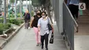 Warga mengenakan masker melintas di trotoar Jalan Jenderal Sudirman, Jakarta, Kamis (9/7/2020). Berdasar data yang diumumkan pemerintah pada Kamis (9/7) ada penambahan 2.657 orang yang terinfeksi COVID-19 sehingga jumlah penderita menjadi 70.736. (Liputan6.com/Helmi Fithriansyah)