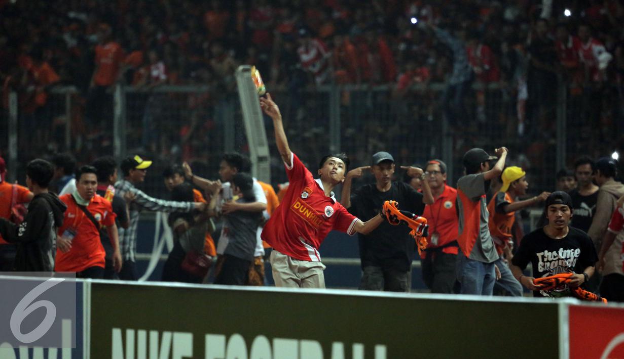 Suporter Persija melempari petugas kepolisian saat terlibat kericuhan pada laga lanjutan Torabika Soccer Championship presented by IM3 Ooredoo antara Persija melawan Sriwijaya FC diStadion GBK Jakarta, Jumat (24/6). (Liputan6.com/Helmi Fithriansyah)