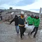 Penyelamat Suriah membawa jenazah melewati bangunan yang runtuh saat operasi pencarian berlanjut setelah gempa mematikan di kota Sarmada, di provinsi Idlib barat laut yang dikuasai pemberontak Suriah pada 6 Februari 2023. Setidaknya 1.400 orang tewas dan 3.411 terluka di seluruh Suriah hari ini dalam gempa bumi yang berpusat di Turki barat daya, kata pemerintah dan penyelamat. (AFP/Aaref Watad)