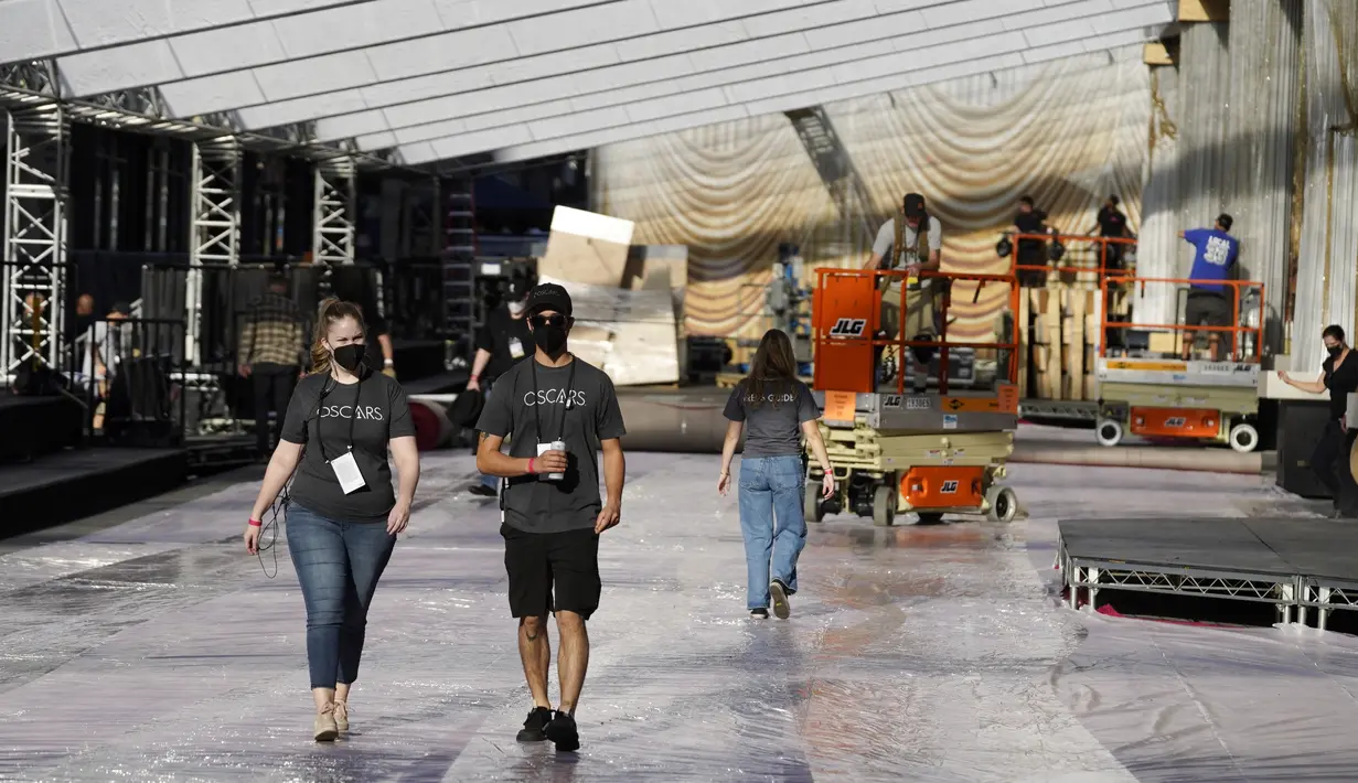 Anggota kru berjalan di area kedatangan karpet merah dalam persiapan untuk Academy Awards ke-94 atau piala Oscar di luar Teater Dolby, Los Angeles, Rabu (23/3/2022). Ajang penghargaan Piala Oscar ke-94 akan diadakan pada Minggu, 27 Maret 2022 di Dolby Theatre Hollywood. (AP Photo/Chris Pizzello)