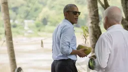 Presiden AS, Barack Obama memegang kelapa bersama duta besar AS untuk Laos Daniel Clune saat ia membuat kejutan ke warga Laos untuk berhenti meminum kelapa di sepanjang Sungai Mekong di Luang Prabang, Laos (7/9). (AFP PHOTO/SAUL Loeb)