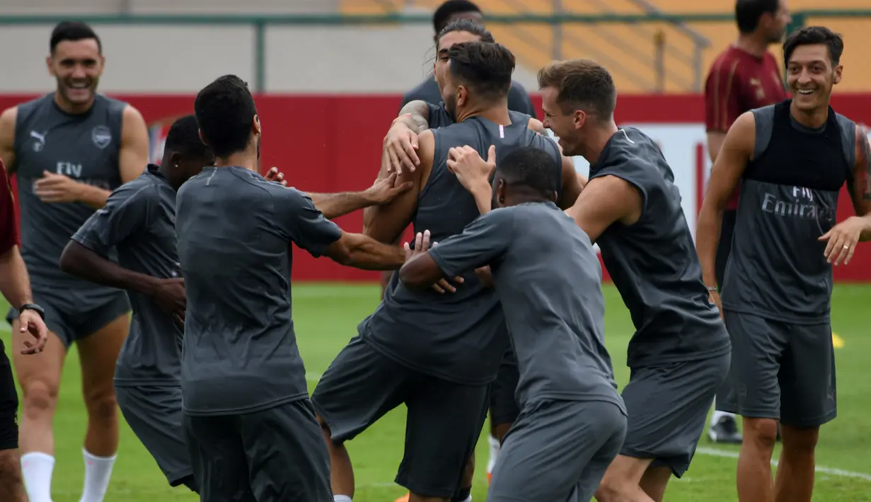 Keceriaan Mesut Ozil dan pemain Arsenal lainnya saat sesi latihan untuk kompetisi pramusim International Champions Cup (ICC) 2018 di Singapura, Rabu (27/5). Menjelang duel kontra Atletico Madrid, Ozil dkk menikmati sesi latihan ringan. (AFP/Roslan RAHMAN)