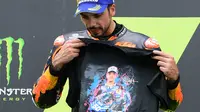 Miguel Oliveira menunjukkan baju bergambar mendiang Jason Dupasquier saat berada di podium teratas balapan MotoGP Catalunya. (LLUIS GENE / AFP)